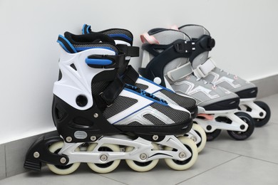 Photo of Pairs of roller skates on floor near white wall