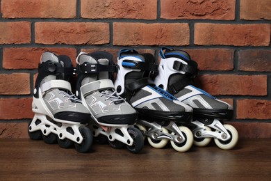 Photo of Pairs of roller skates on wooden table near brick wall