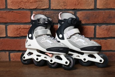 Photo of Pair of roller skates on wooden table near brick wall