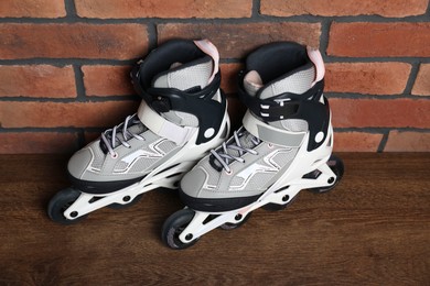 Photo of Pair of roller skates on wooden table near brick wall