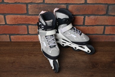Photo of Pair of roller skates on wooden table near brick wall