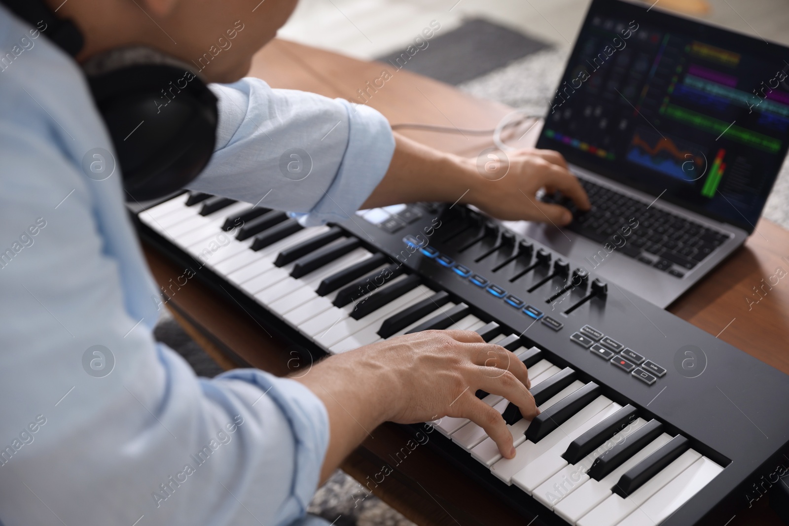 Man working with MIDI keyboard and laptop at table indoors, selective focus Photo of Man working with MIDI keyboard and laptop at table indoors, selective focus