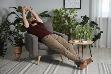Photo of Harmony. Man relaxing in comfortable armchair at home