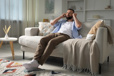 Photo of Harmony. Man listening to music in headphones on sofa at home