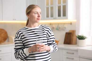 Photo of Young woman with glass of water in kitchen