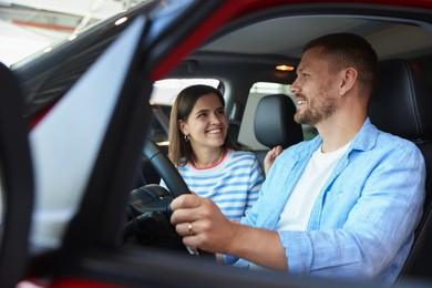 Photo of Happy family sitting inside new car. Luxury vehicle