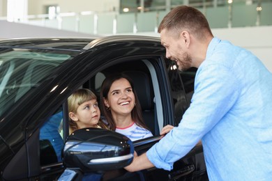 Photo of Happy family and new car in salon