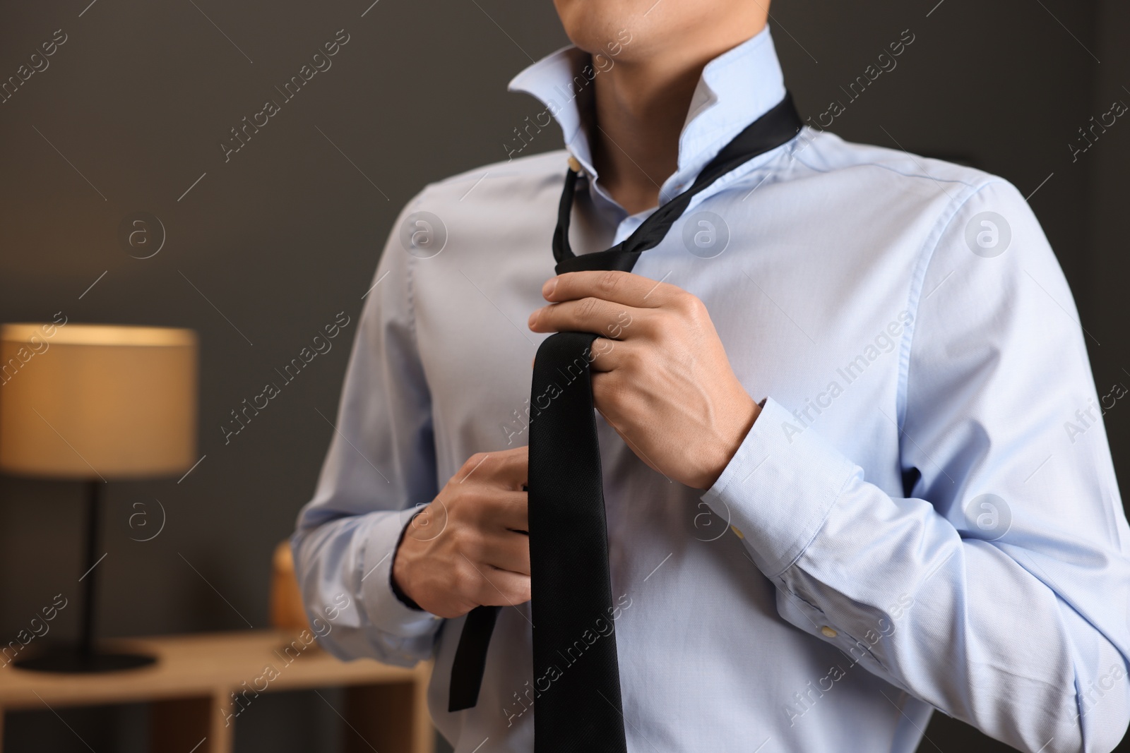 Man tying stylish necktie at home, closeup Photo of Man tying stylish necktie at home, closeup