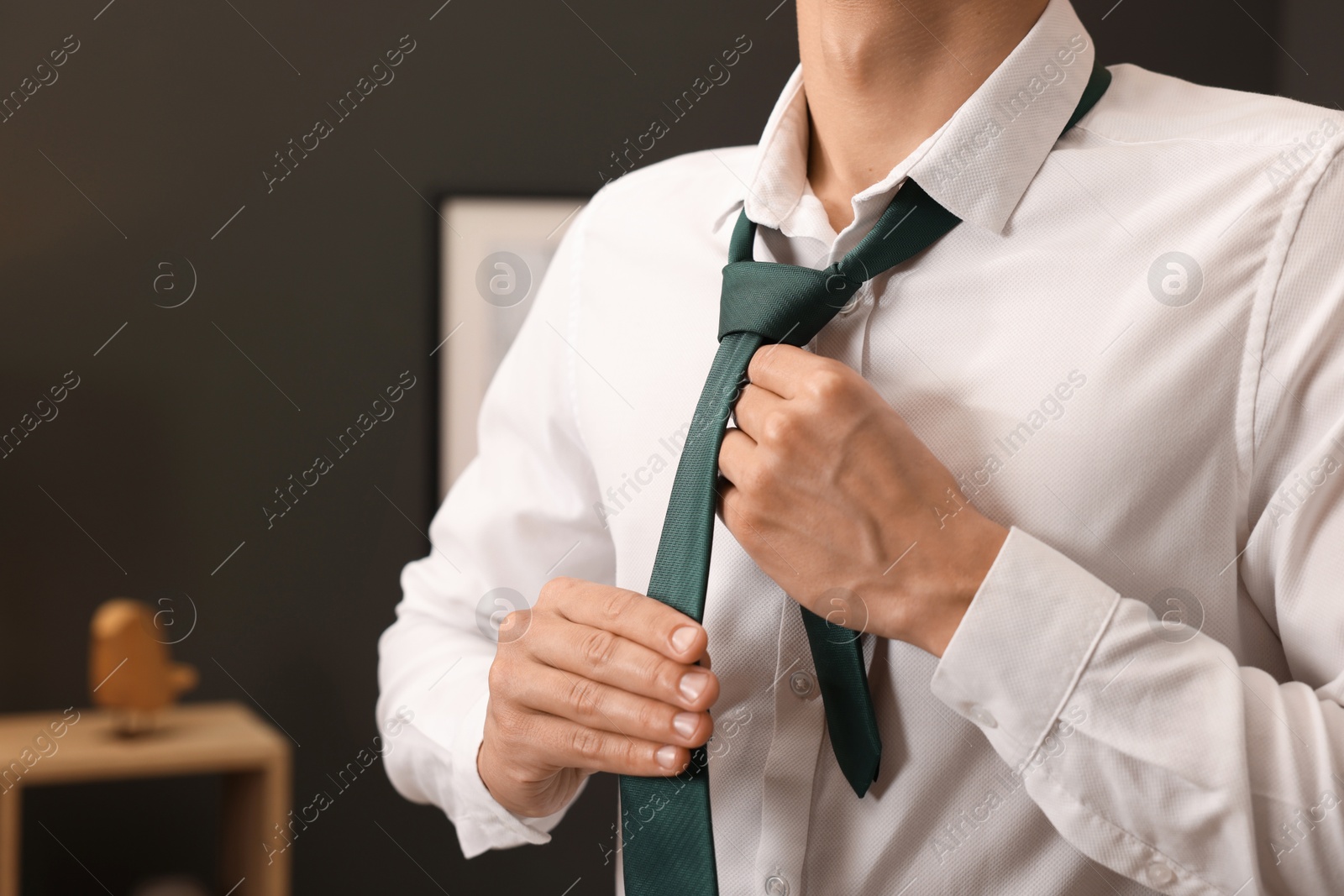 Man tying stylish necktie at home, closeup Photo of Man tying stylish necktie at home, closeup