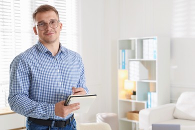 Photo of Portrait of psychologist in glasses with notepad in office. Space for text