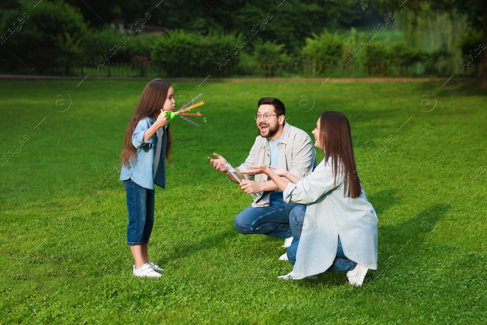 Happy family playing with soap bubbles in park Photo of Happy family playing with soap bubbles in park