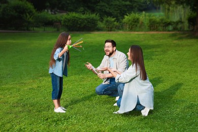 Photo of Happy family playing with soap bubbles in park