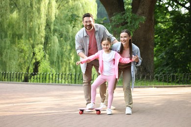 Photo of Happy family having fun with penny board in park