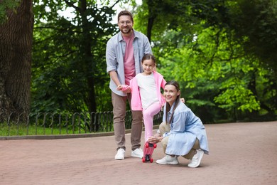 Photo of Happy family having fun with penny board in park