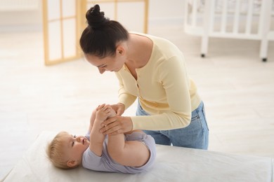 Photo of Mother playing with her cute baby on changing table at home