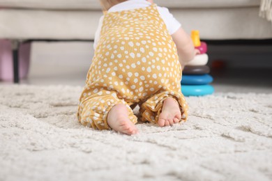 Photo of Cute little baby playing with toy pyramid on floor at home, back view