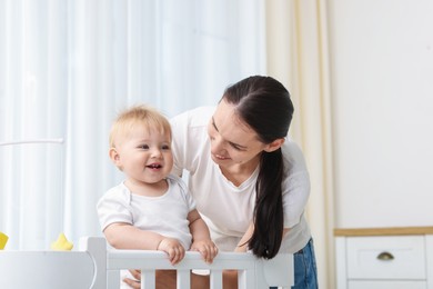 Photo of Mother playing with her cute baby in crib at home