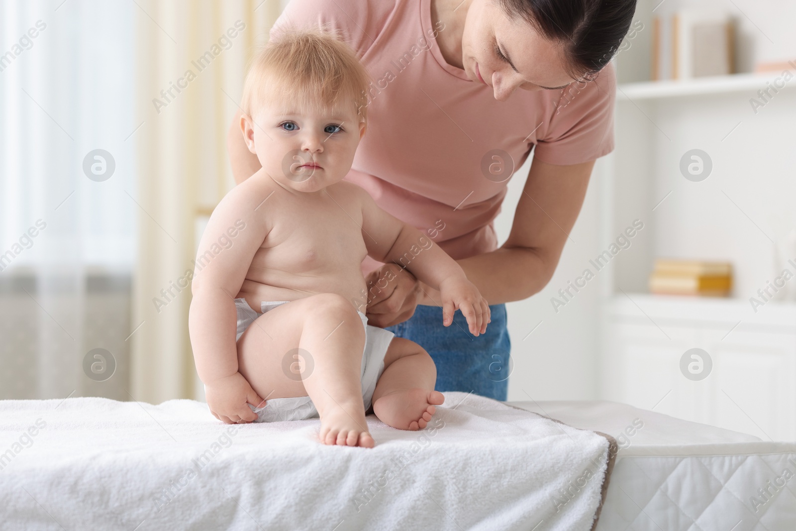 Photo of Mother changing her baby's diaper on table at home