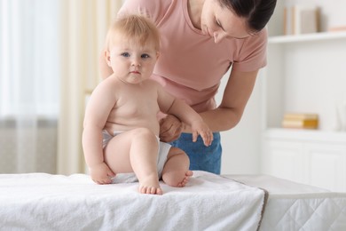 Photo of Mother changing her baby's diaper on table at home