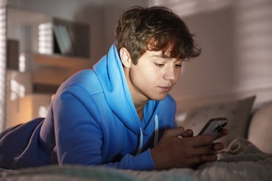 Photo of Teenage boy using smartphone on bed at home