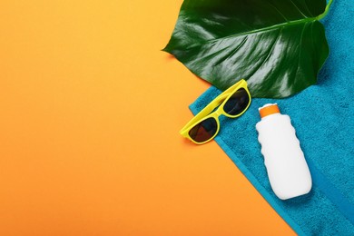 Photo of Beach towel, sunglasses, sunscreen and leaf on orange background, flat lay. Space for text