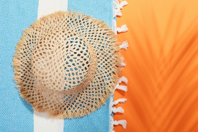 Photo of Hat and beach towel on orange background, top view. Space for text