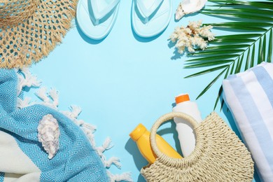 Photo of Frame of beach accessories, sea shells and palm leaf on light blue background, flat lay. Space for text