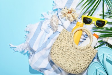 Photo of Beach accessories, sea shells and palm leaves on light blue background, flat lay