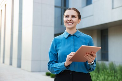 Photo of Happy businesswoman with tablet near office building. Space for text