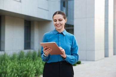 Photo of Happy businesswoman with tablet near office building