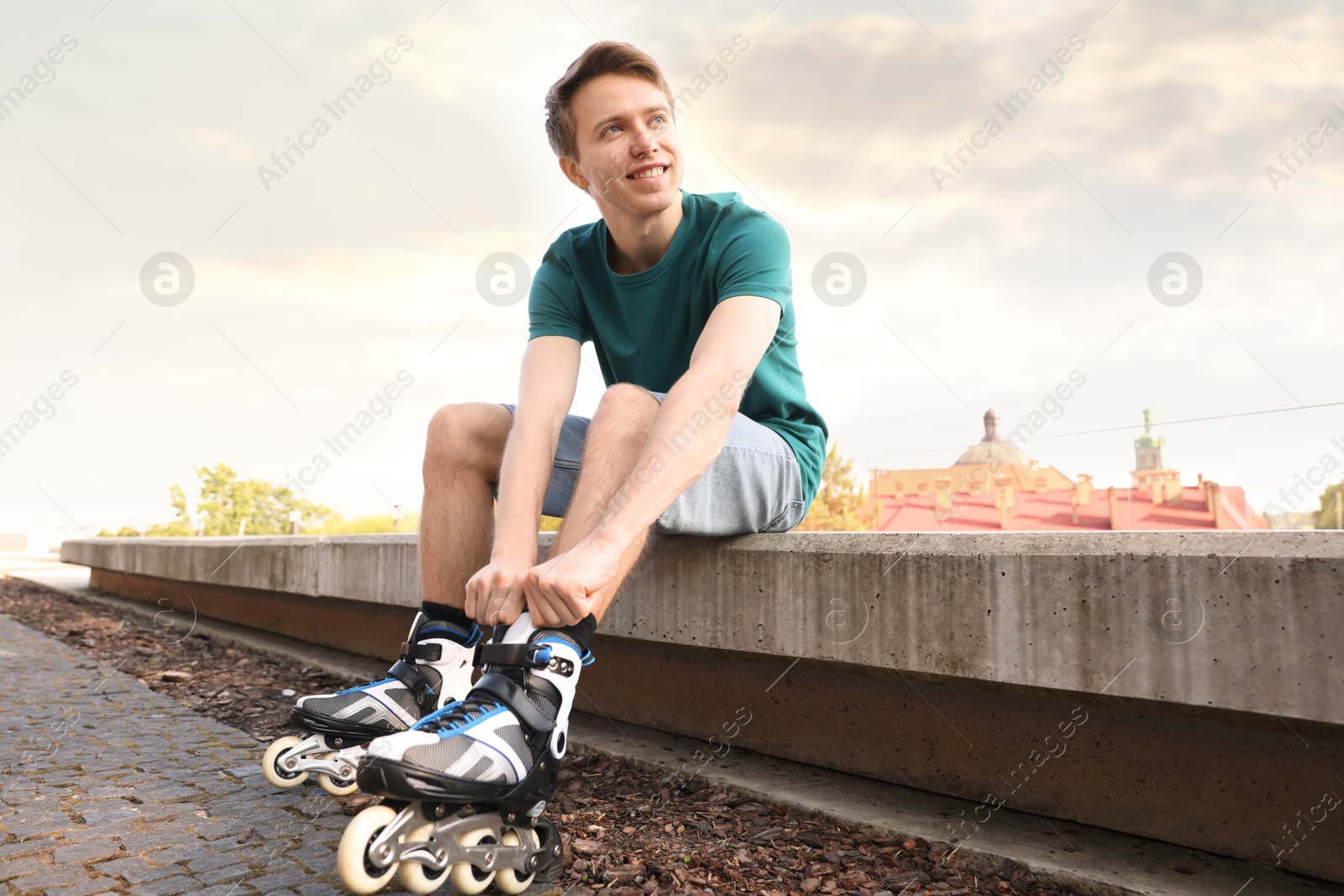 Happy man putting on roller skates outdoors Photo of Happy man putting on roller skates outdoors