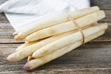 Photo of Raw white asparagus spears on wooden table, closeup