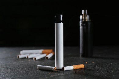 Photo of Electronic smoking devices and cigarettes on black table