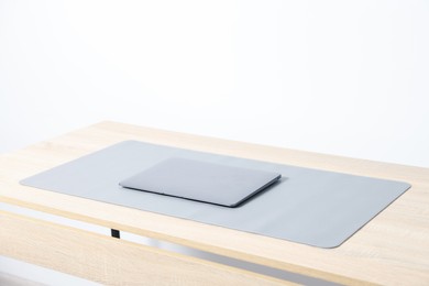 Photo of Stylish workplace with laptop and grey mousepad on wooden table indoors. Space for text