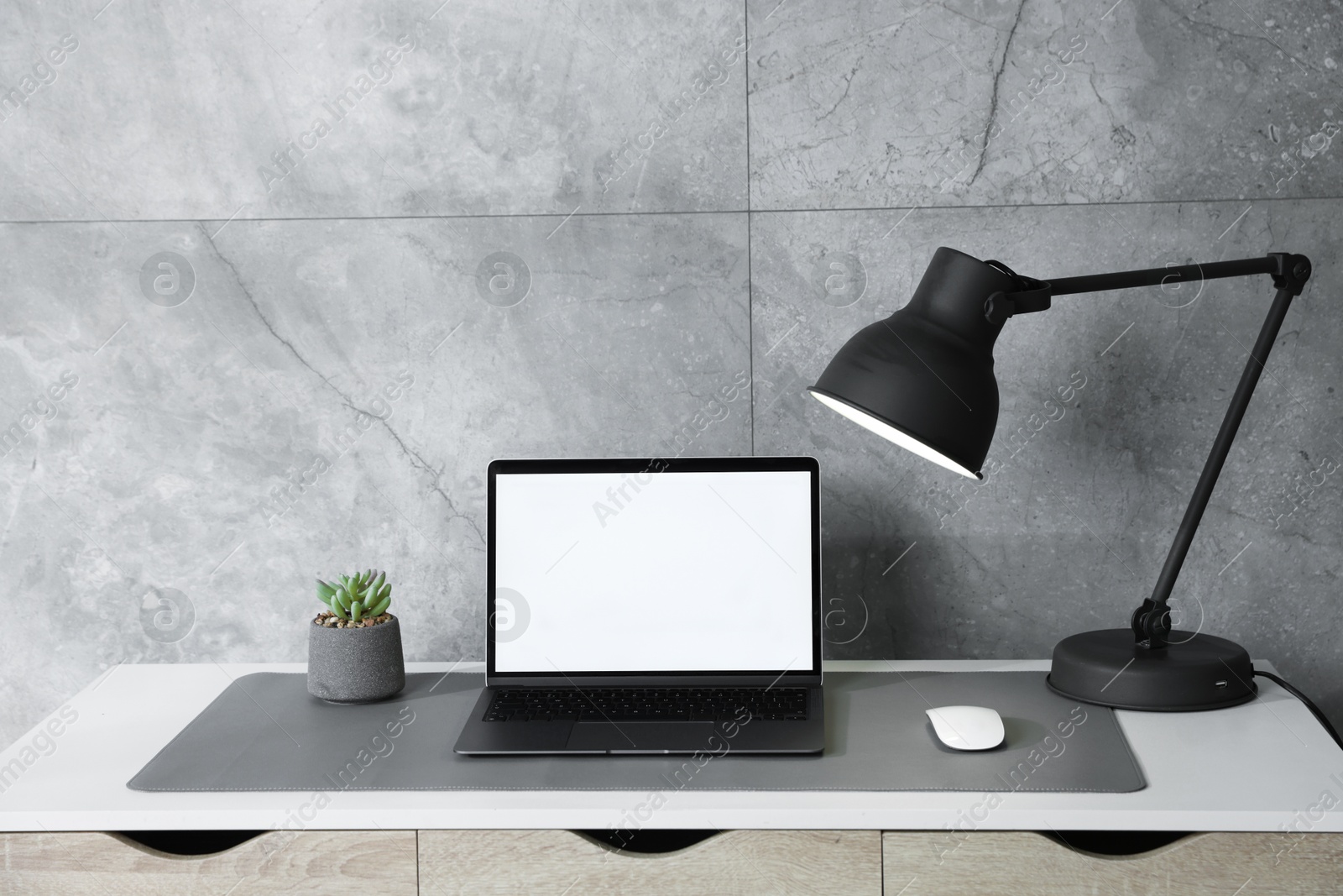 Photo of Stylish workplace with laptop and grey mousepad on white table indoors. Space for text