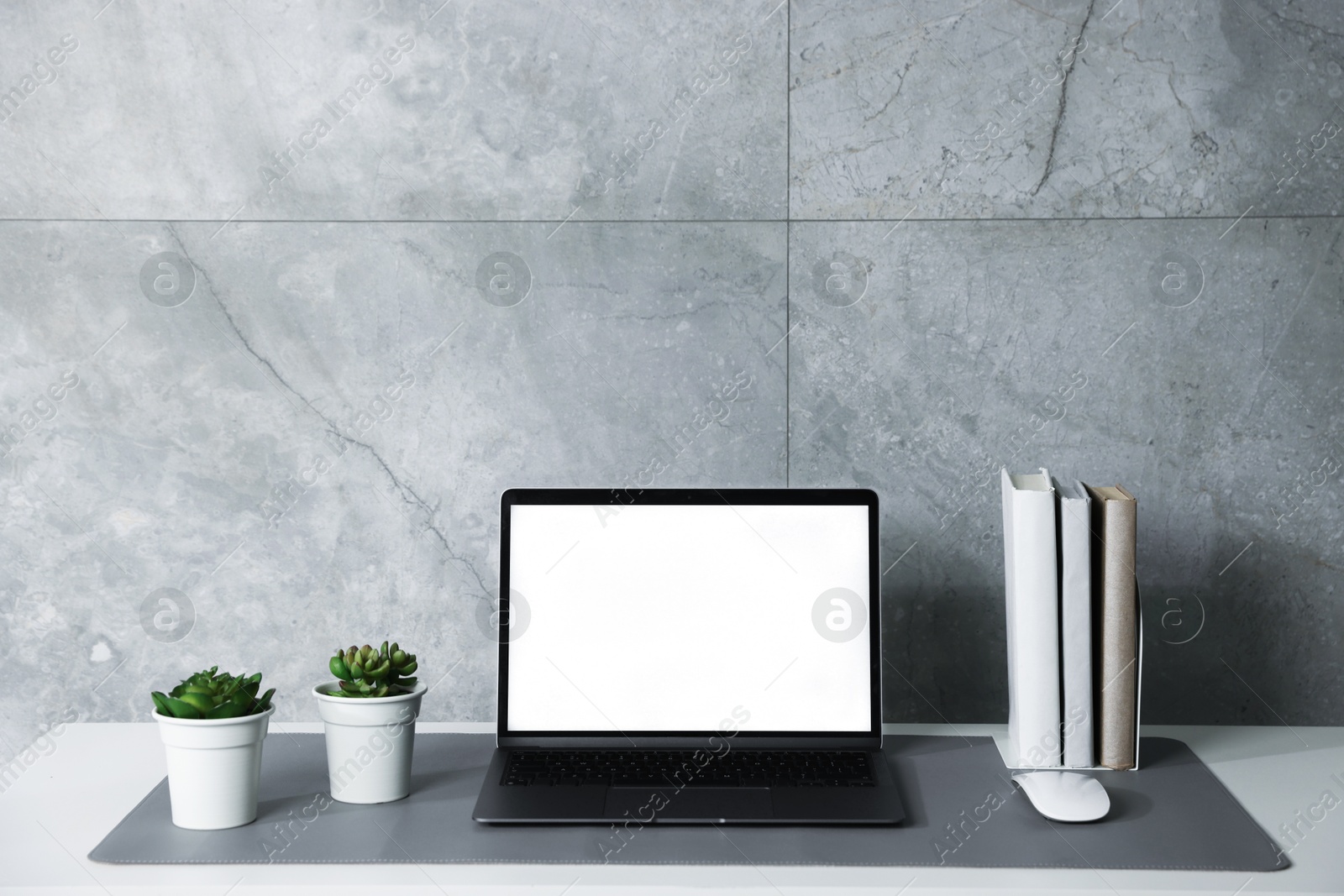 Photo of Stylish workplace with laptop and grey mousepad on white table indoors. Space for text