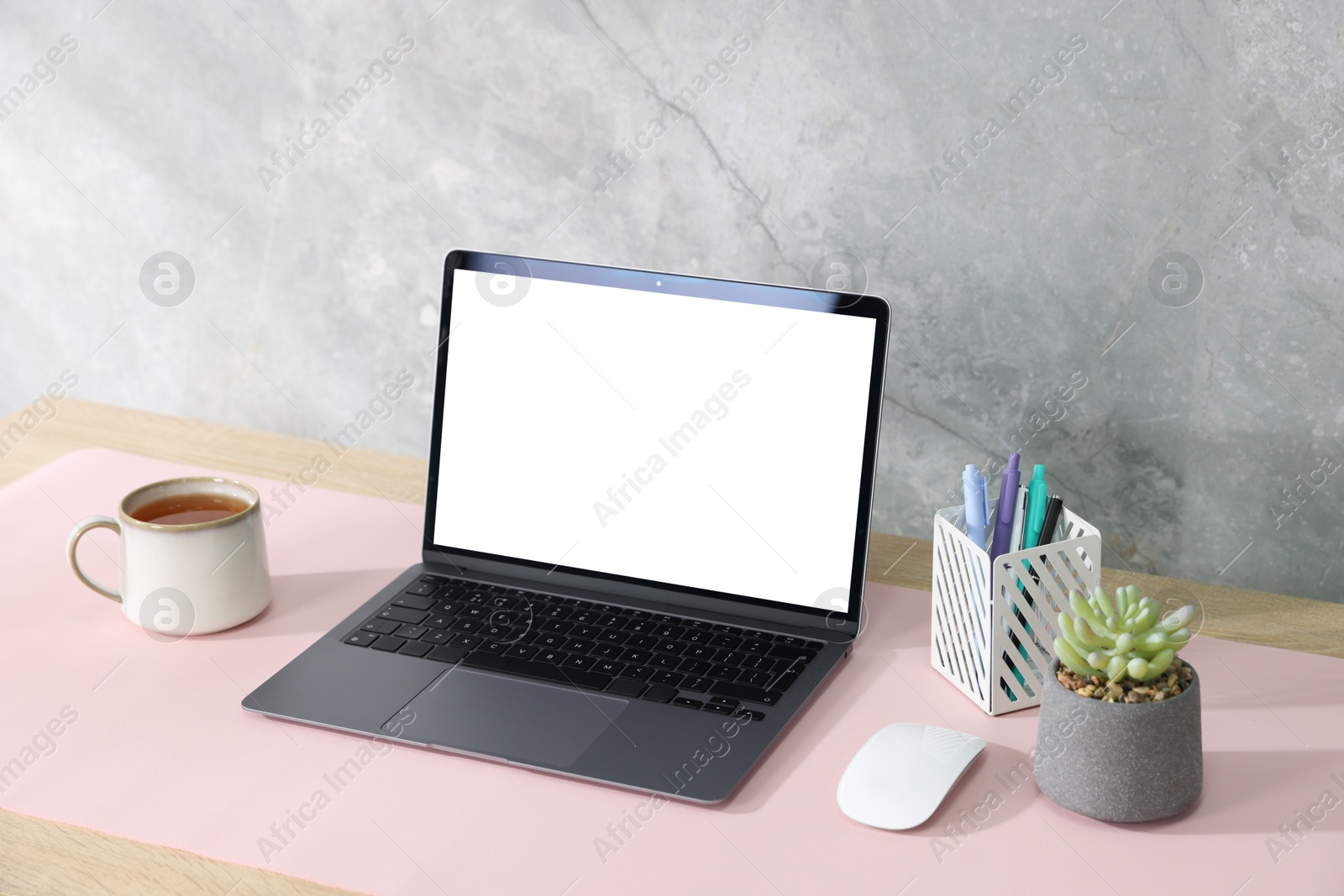 Photo of Stylish workplace with laptop and pink mousepad on white table indoors. Space for text