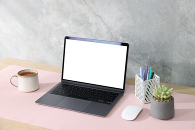 Photo of Stylish workplace with laptop and pink mousepad on white table indoors. Space for text