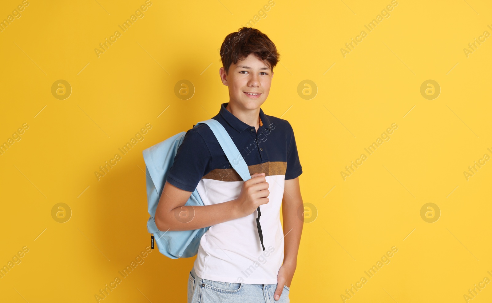 Teenage boy with backpack on orange background Photo of Teenage boy with backpack on orange background