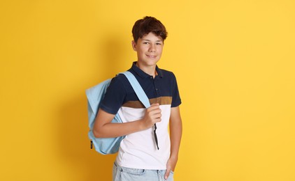 Photo of Teenage boy with backpack on orange background