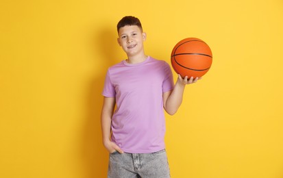 Photo of Teenage boy with basketball ball on orange background