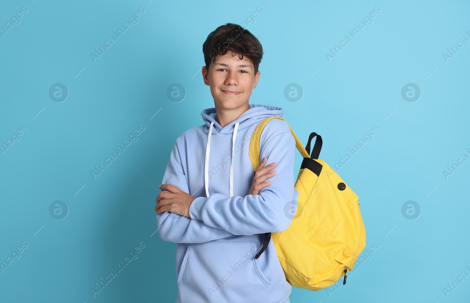 Teenage boy with backpack on light blue background Photo of Teenage boy with backpack on light blue background
