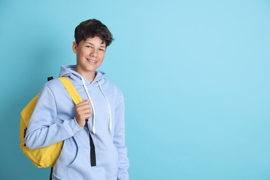 Photo of Teenage boy with backpack on light blue background, space for text