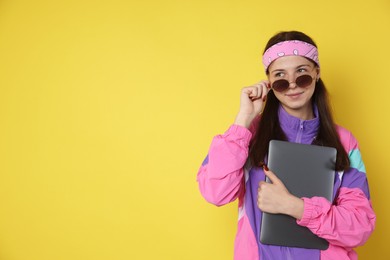 Photo of Teenage girl in sunglasses with laptop on yellow background, space for text