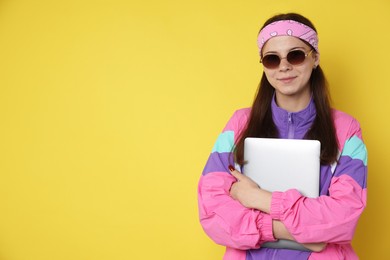 Photo of Teenage girl in sunglasses with laptop on yellow background, space for text