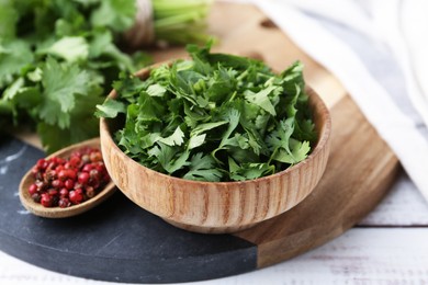 Photo of Fresh green cilantro and peppercorns on white wooden table, closeup