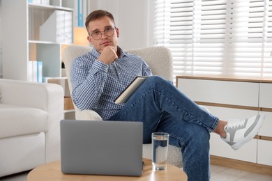 Photo of Psychologist in glasses with notepad in front of laptop in office