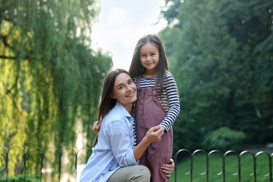 Photo of Family portrait of smiling mother and daughter in park