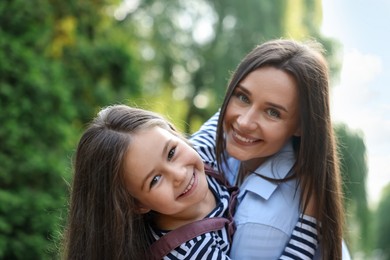 Photo of Family portrait of smiling mother and daughter in park