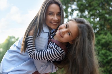 Photo of Family portrait of smiling mother and daughter in park